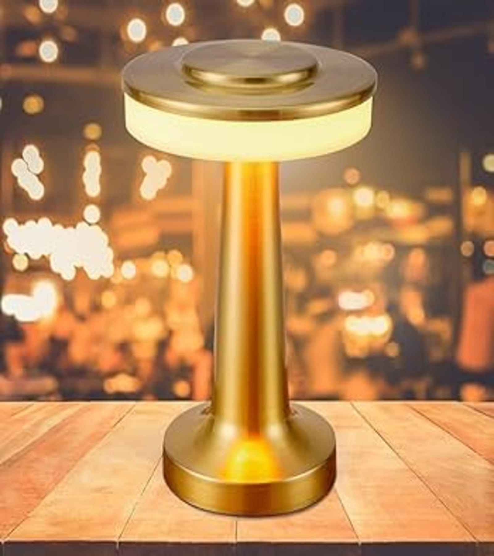 Modern golden rechargeable cordless table lamp glowing on a wooden table
