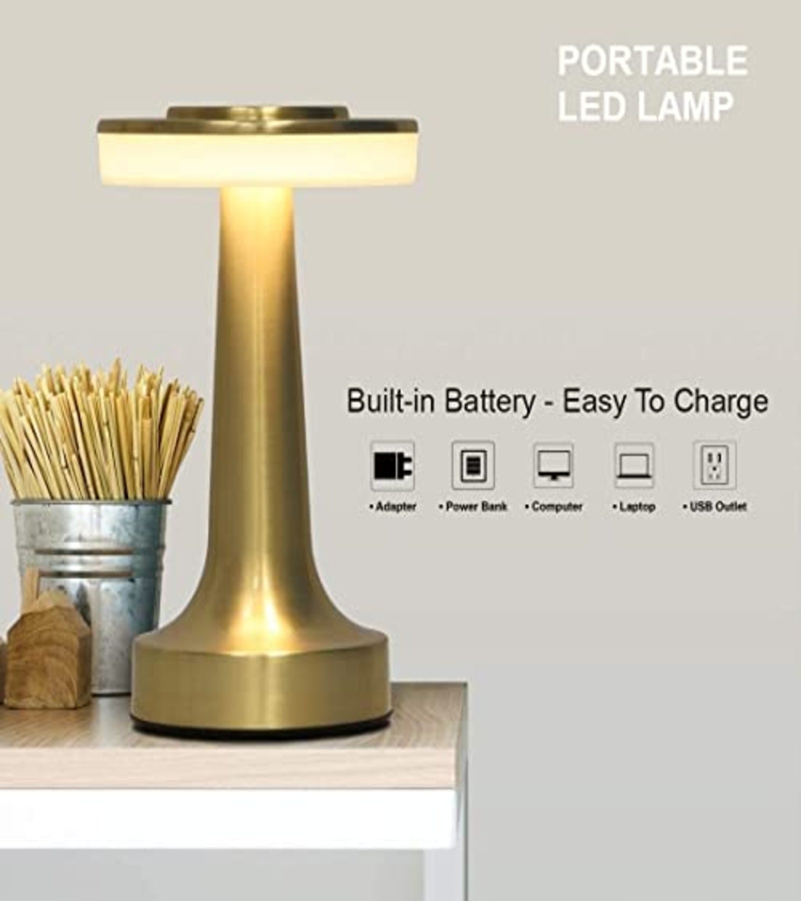 Gold portable LED lamp with built-in battery on a wooden desk
